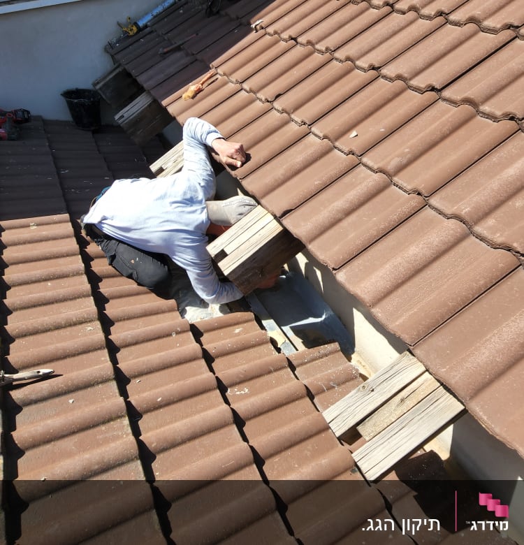 אדם מתקן רעפים על גג חום עם כלים